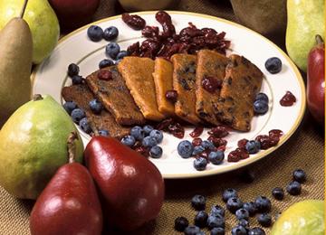 A plate of pear bars surrounded by blueberries and pears.