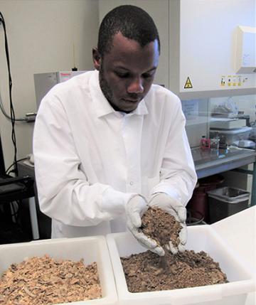 Adelumola Oladeinde with two containers of litter collected from a broiler house.