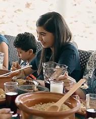 A smiling, multi-generational group of people sits at a table set with food.